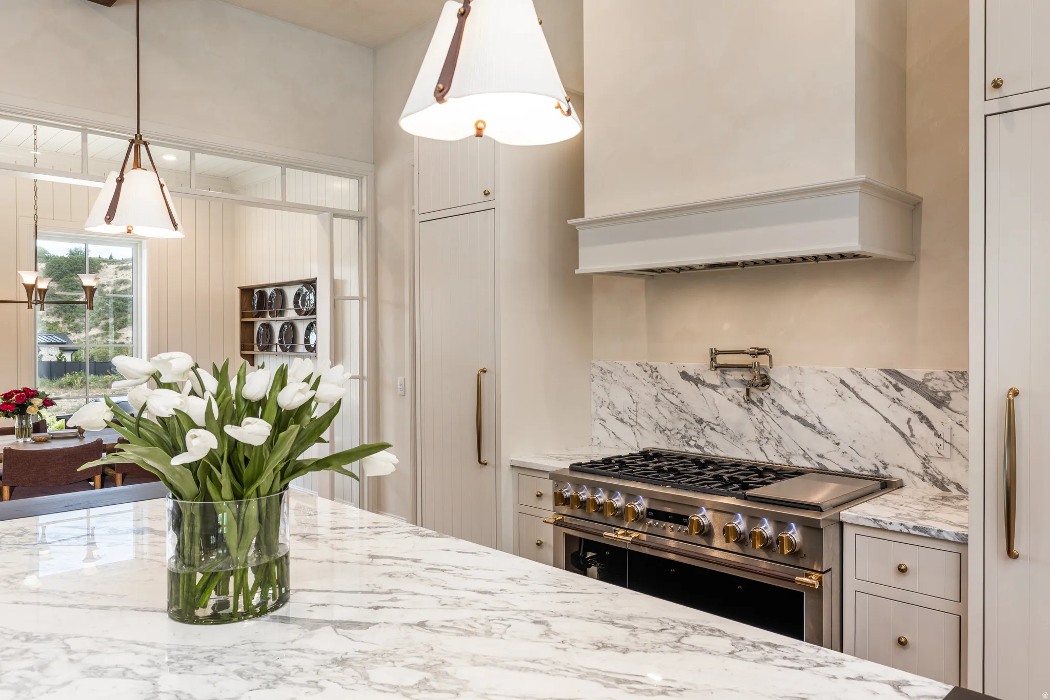 Gourmet kitchen featuring a professional-grade gas range with a pot filler, a custom range hood, and extensive stone countertops with matching backsplash
