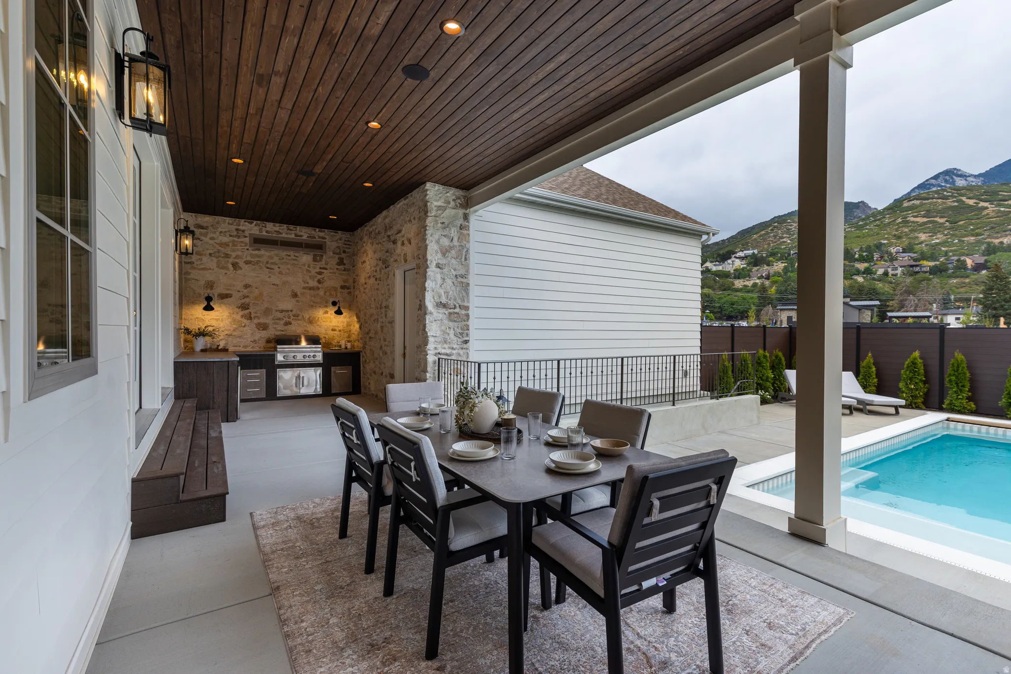 Covered patio featuring an outdoor kitchen with built-in grill, stone accent wall, wood-finish ceiling, and recessed lighting