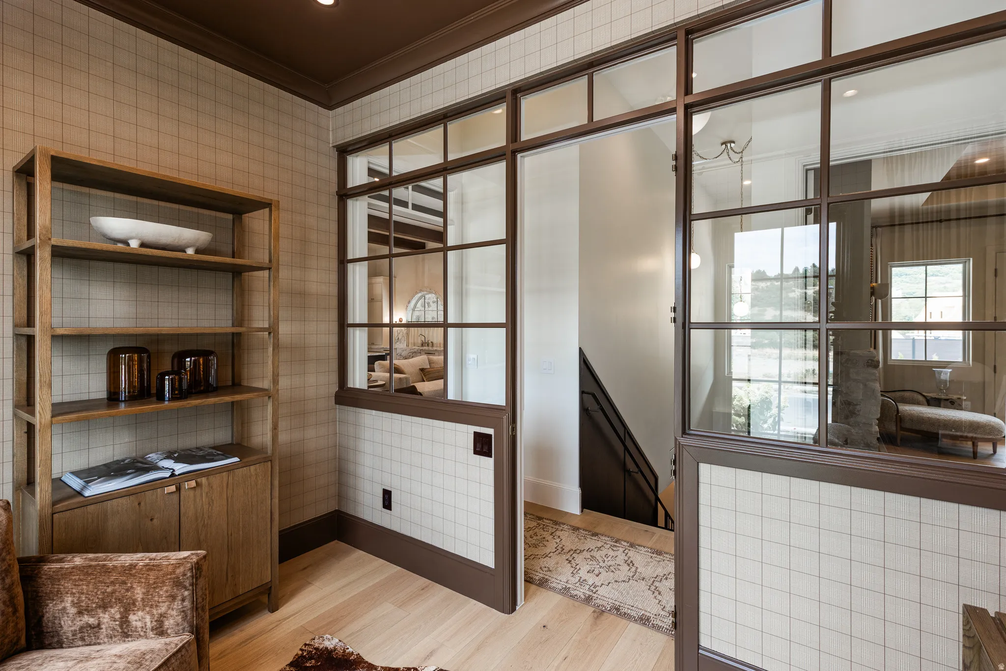 Room featuring grid-patterned wall finish, light wood-finish flooring, and a built-in wood shelving unit