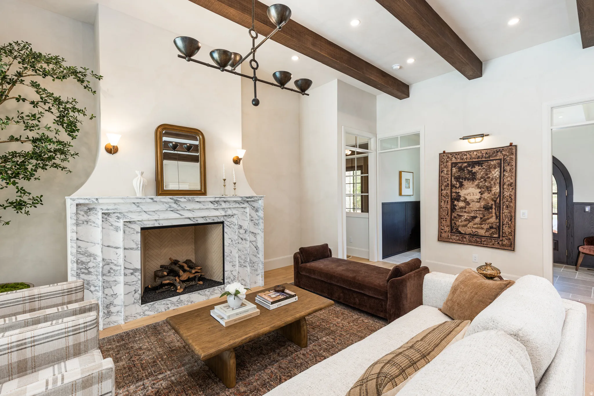Living area featuring a prominent fireplace with a marble surround and hearth, wood-finish flooring, exposed wood ceiling beams, and recessed lighting