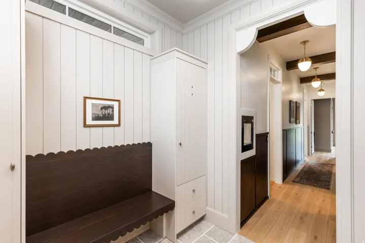 Entryway featuring vertical shiplap paneling, a dark wood built-in bench, a built-in storage cabinet with drawers, and transom window
