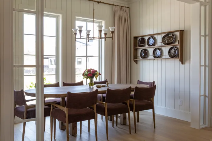 Vertical plank wall paneling with a built-in display shelf, wood-finish flooring, a multi-pane glass door, and expansive windows