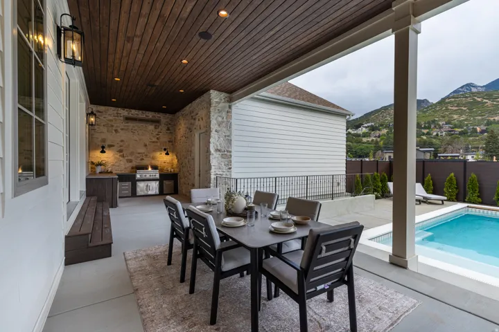 Covered patio featuring an outdoor kitchen with built-in grill, stone accent wall, wood-finish ceiling, and recessed lighting