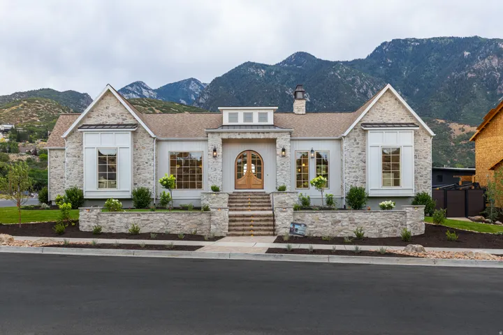 Stone and board-and-batten exterior with an arched wood entry door, multiple gables, and large windows