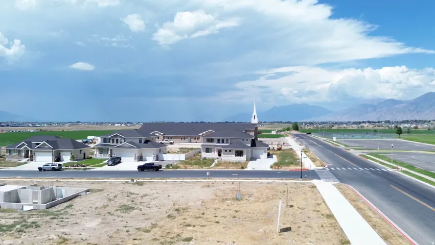 New construction home surrounded by open land, featuring an asphalt driveway and a two-car garage