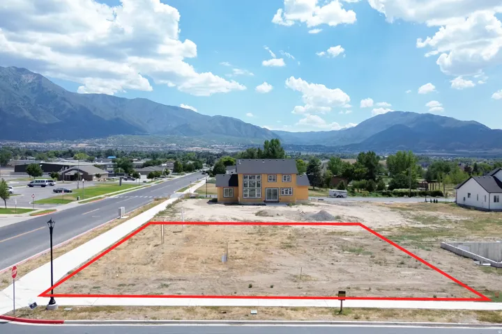 Expansive undeveloped lot featuring street frontage with existing sidewalk and mountain backdrop
