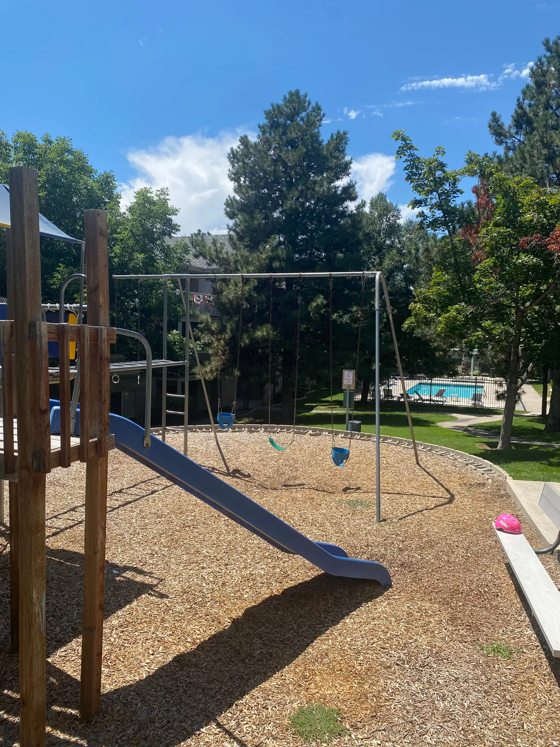 Playground area featuring a blue slide, swing set, and wood chip surfacing