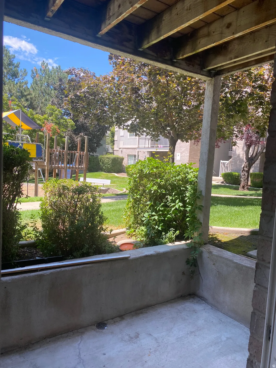 Private concrete patio area with a wooden overhead structure