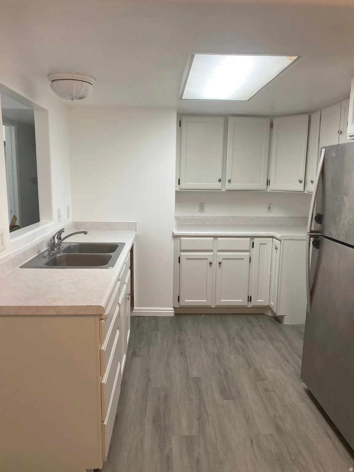 Kitchen featuring wood-finish flooring and white cabinetry