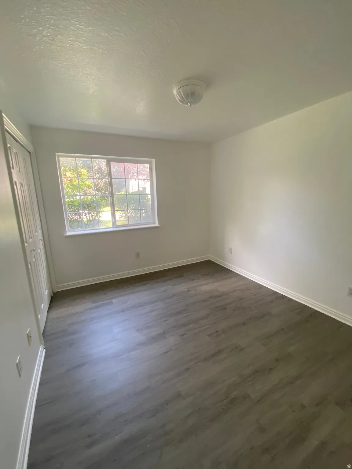 Interior space featuring wood-finish flooring, white walls, and a window with natural light