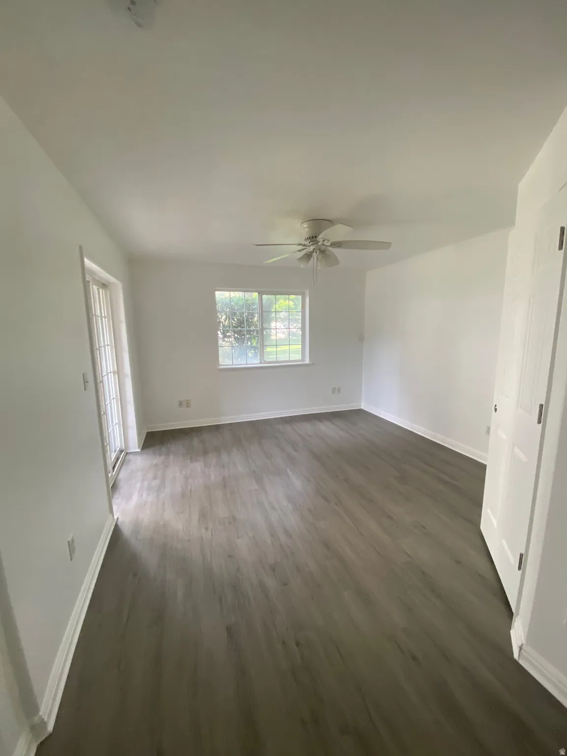 Spacious interior featuring wood-finish flooring, white baseboards, and a ceiling fan