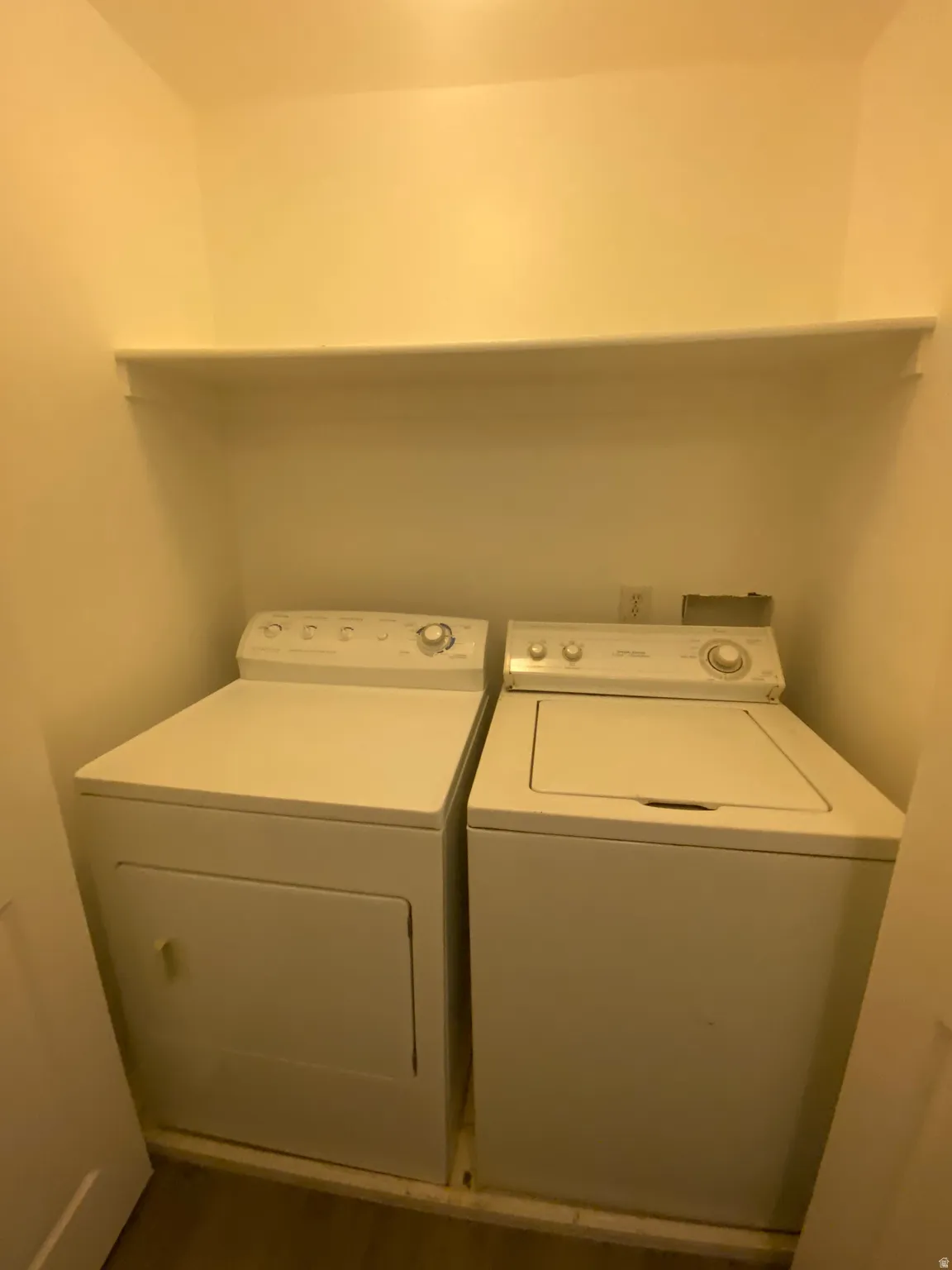Dedicated laundry closet featuring a built-in shelf, white washer, and white dryer