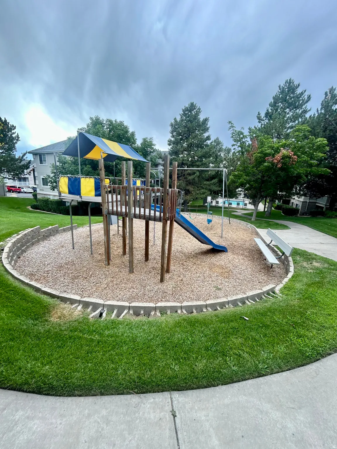 Recreational playground featuring a slide, swings, and a blue and yellow canopy