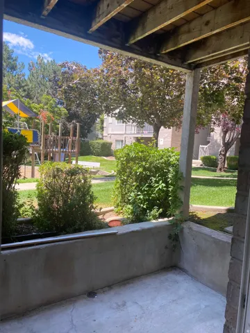 Private concrete patio area with a wooden overhead structure