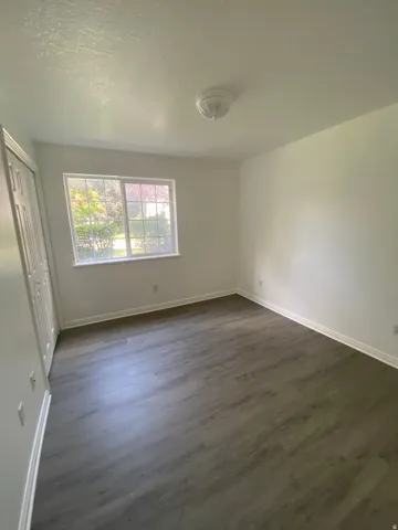 Interior space featuring wood-finish flooring, white walls, and a window with natural light