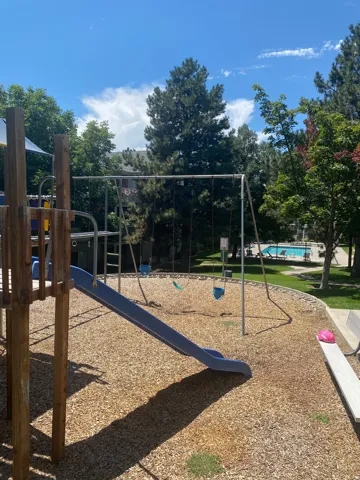 Playground area featuring a blue slide, swing set, and wood chip surfacing