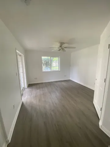 Spacious interior featuring wood-finish flooring, white baseboards, and a ceiling fan