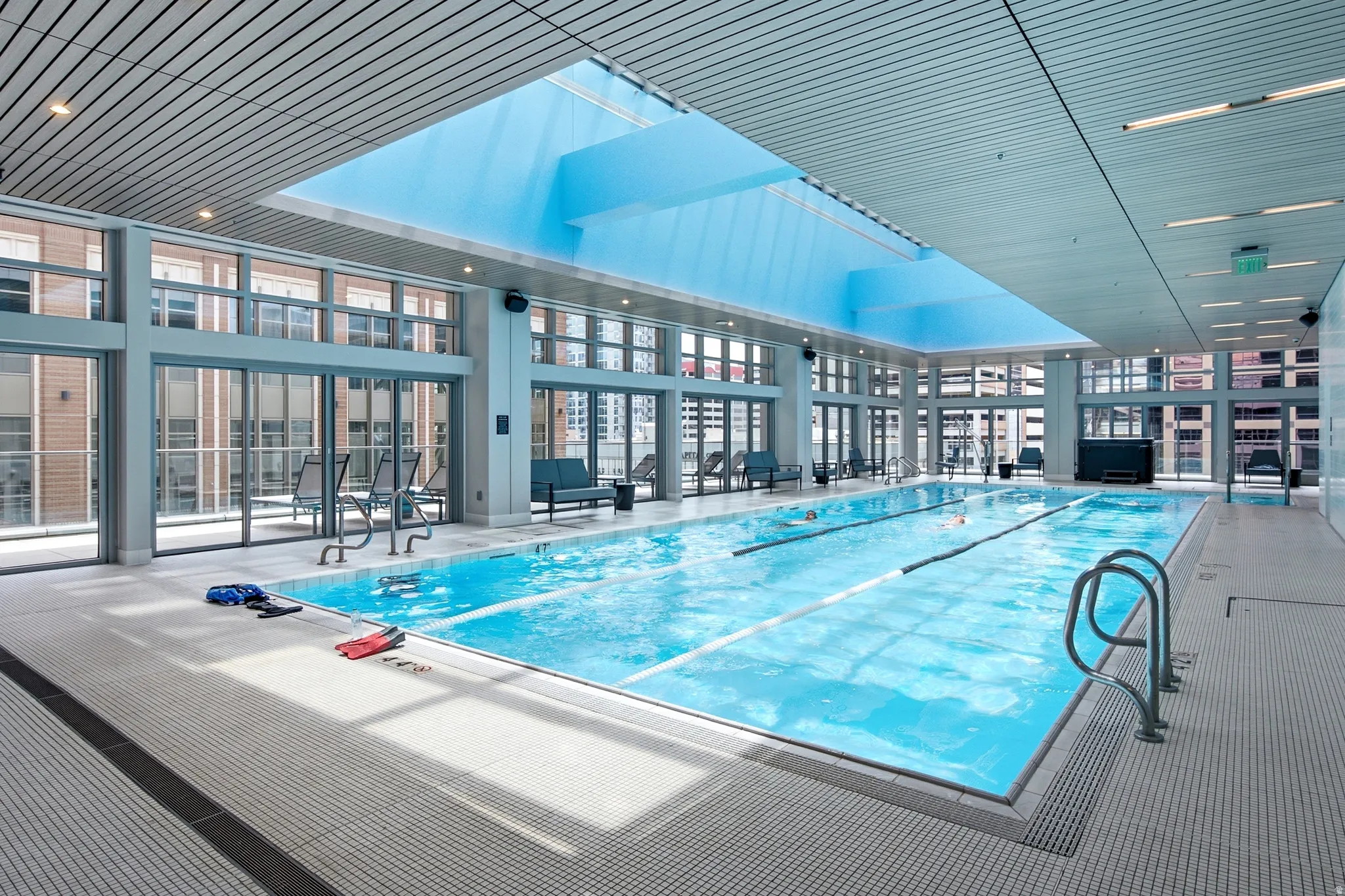 Indoor lap pool featuring a skylight, full-height windows, a tiled deck, and recessed lighting