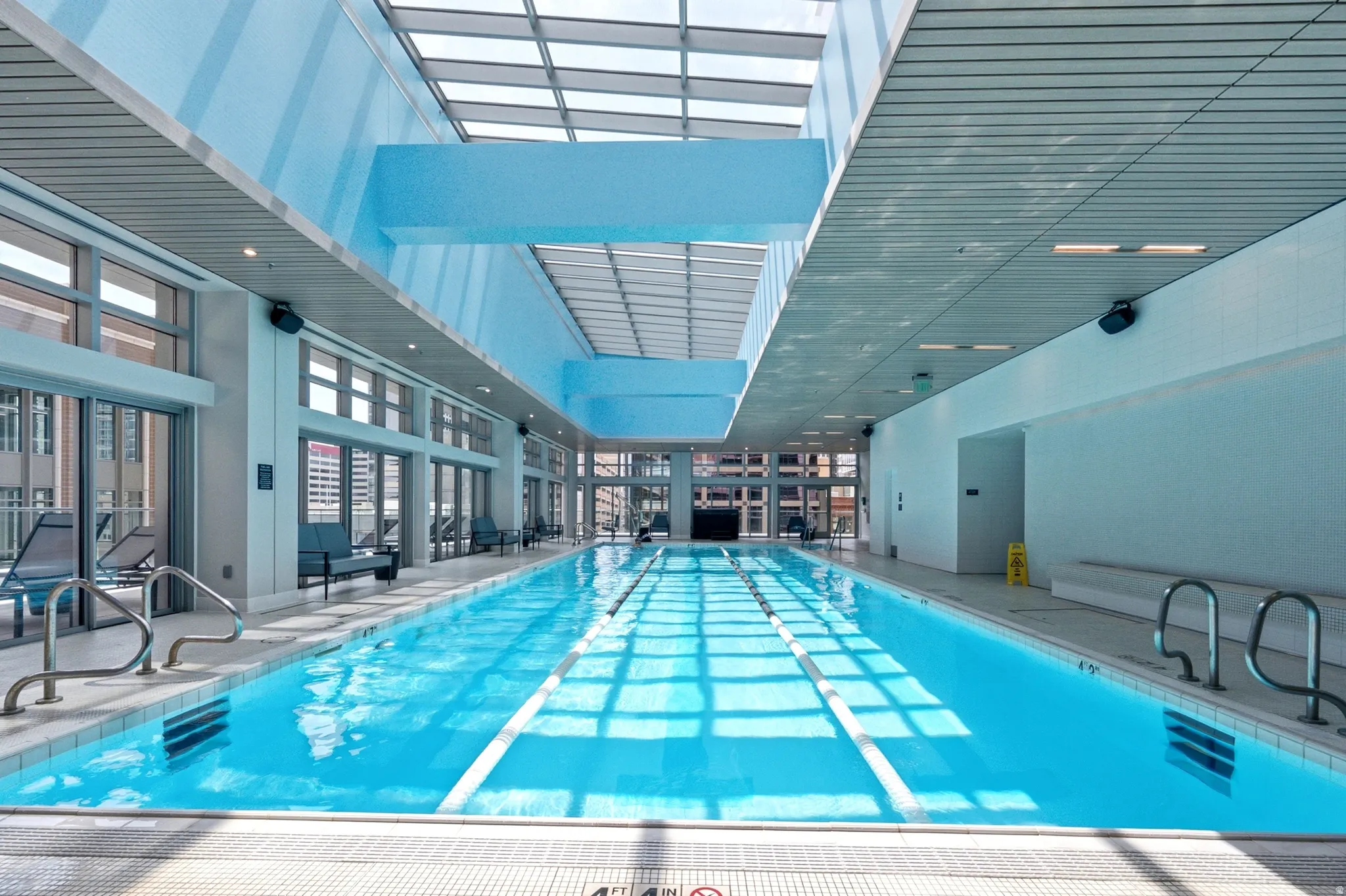 Indoor lap pool featuring a full-length skylight, floor-to-ceiling windows, and recessed lighting