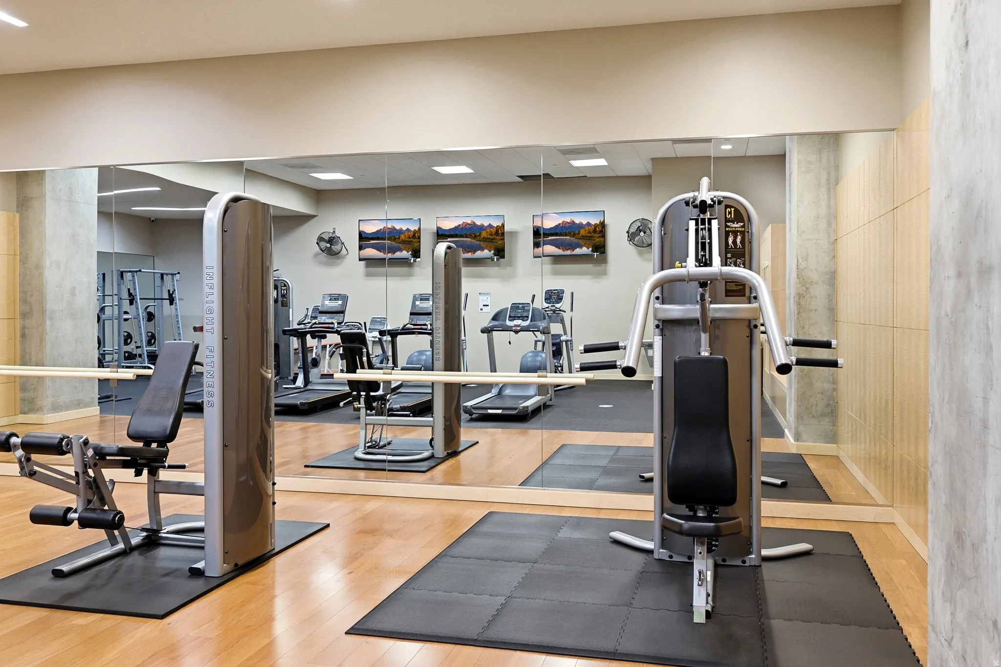 Fitness center featuring hardwood flooring, mirrored walls, and multiple exercise machines