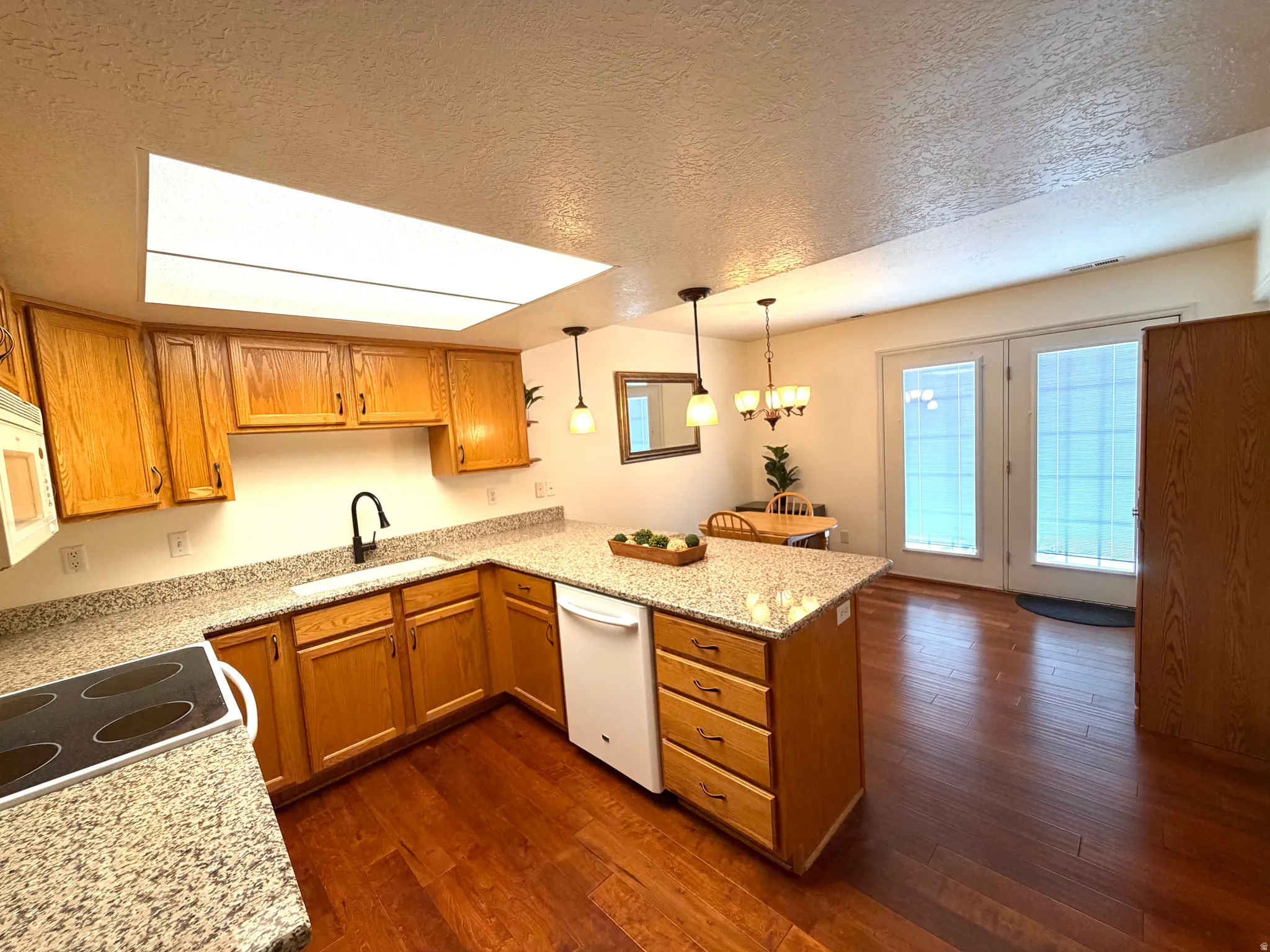 Kitchen featuring wood-finish cabinetry, granite-finish countertops, and a built-in electric stovetop