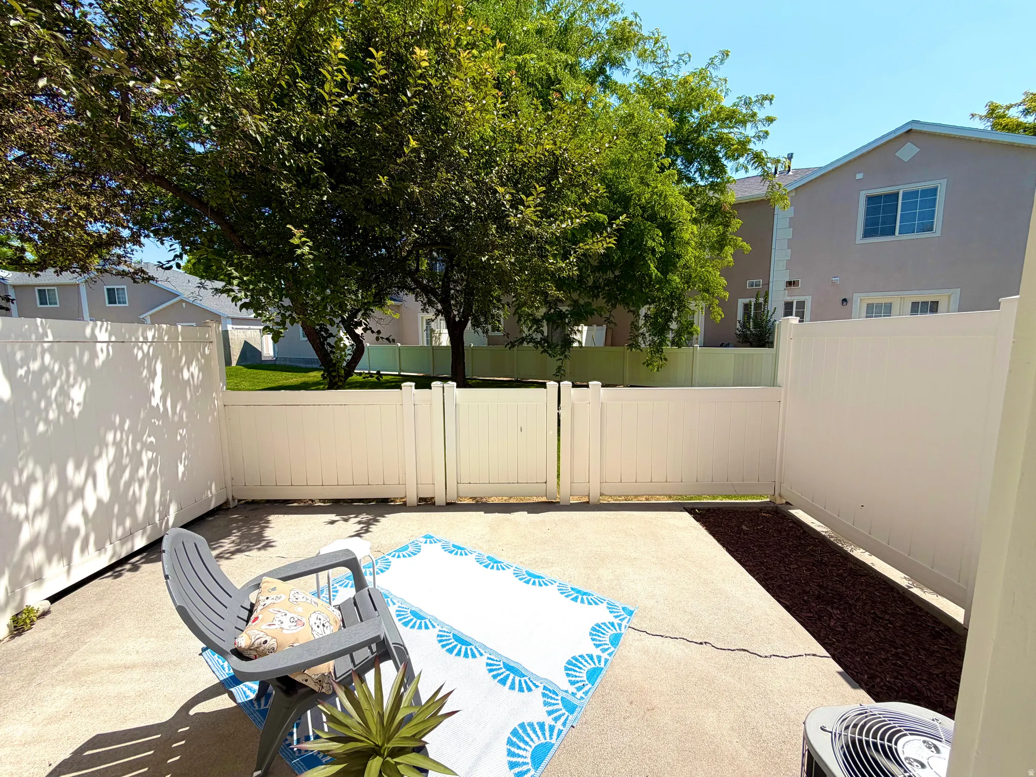 Private outdoor patio with concrete paving, fully enclosed with white fencing, and a mulched border