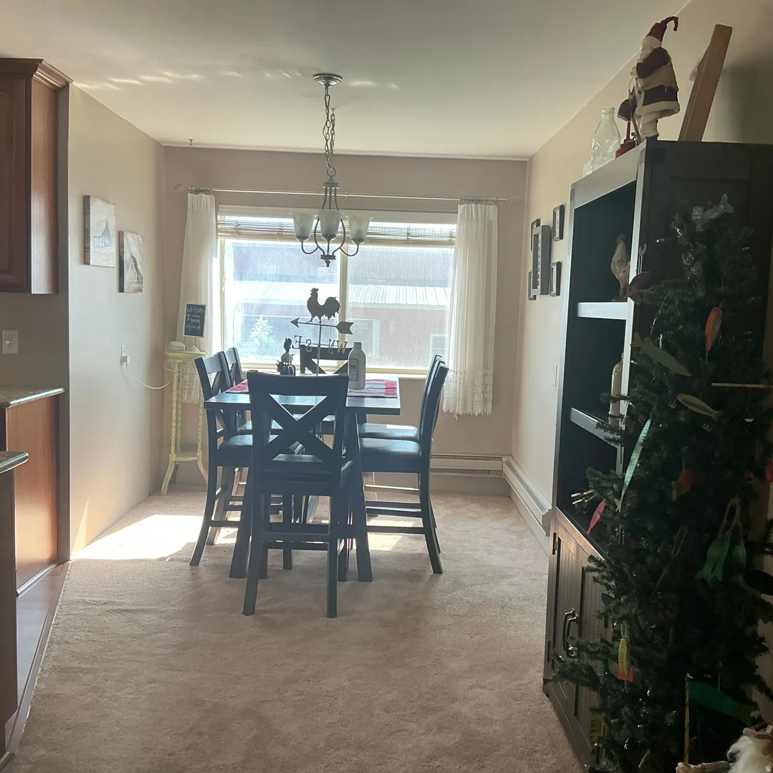 Carpeted dining area featuring a window with white blinds, a multi-light chandelier, and a built-in dark wood cabinetry with shelving