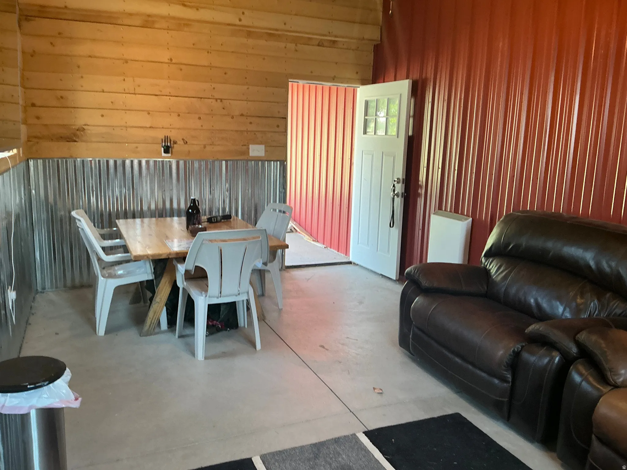 Interior space featuring wood paneling, corrugated metal wainscoting, and concrete flooring
