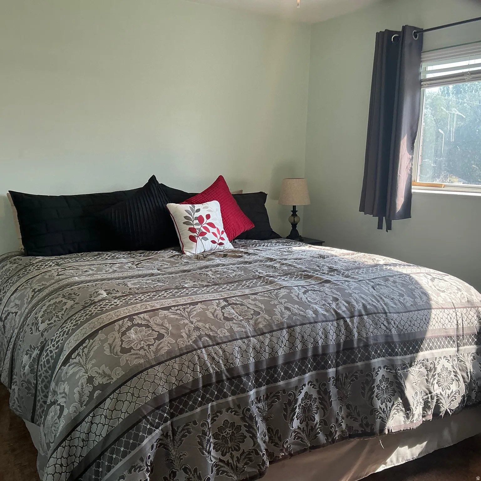 Bedroom featuring light green wall paint, a window with dark curtain panels, and a ceiling fan