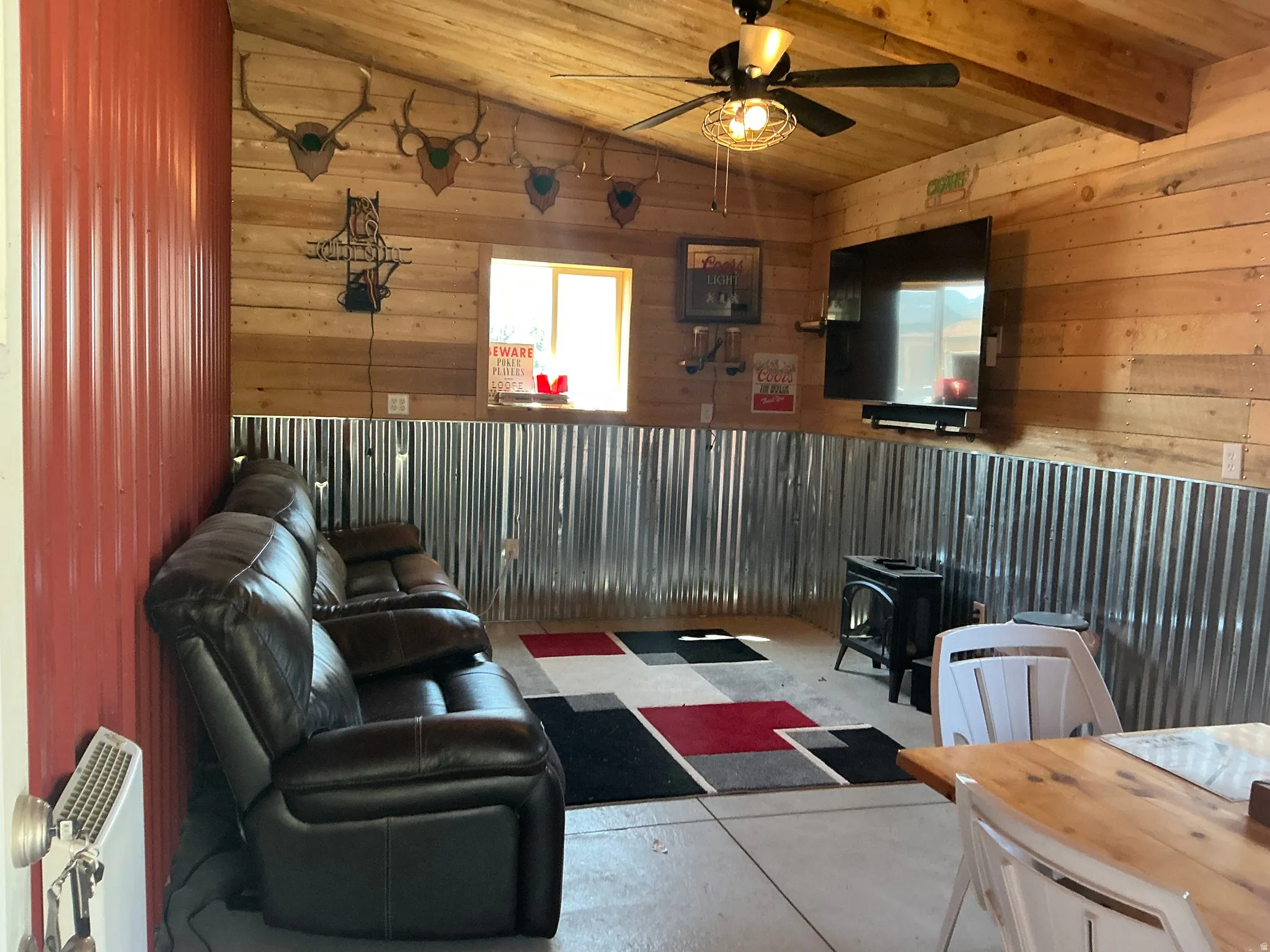 Interior space featuring wood-finish paneling, corrugated metal wainscoting, and a wood-finish ceiling with exposed beams