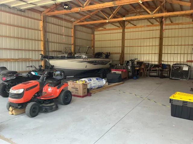 Spacious outbuilding featuring a concrete floor, exposed wooden rafters, corrugated metal walls, and ample overhead clearance