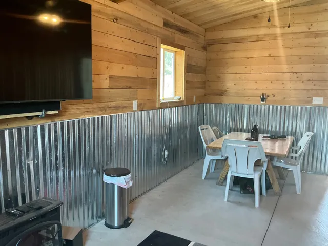 Interior space featuring natural wood plank walls and ceiling, corrugated metal wainscoting, a single window, and concrete flooring