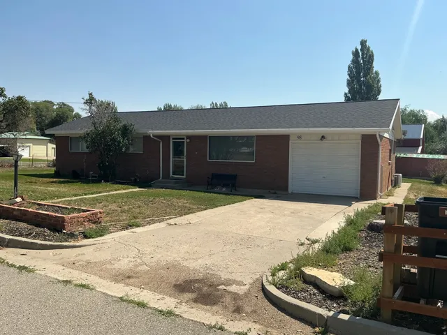 Brick ranch-style residence featuring a dark shingle roof, attached single-car garage with a white door, and a concrete driveway
