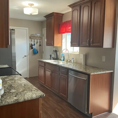 Kitchen featuring wood-finish flooring, dark wood cabinetry, and speckled countertops
