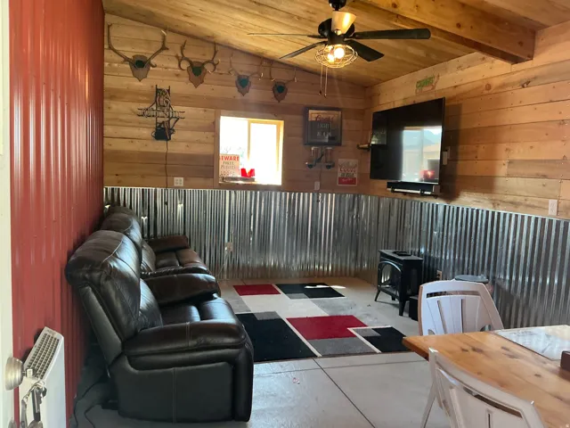 Interior space featuring wood-finish paneling, corrugated metal wainscoting, and a wood-finish ceiling with exposed beams