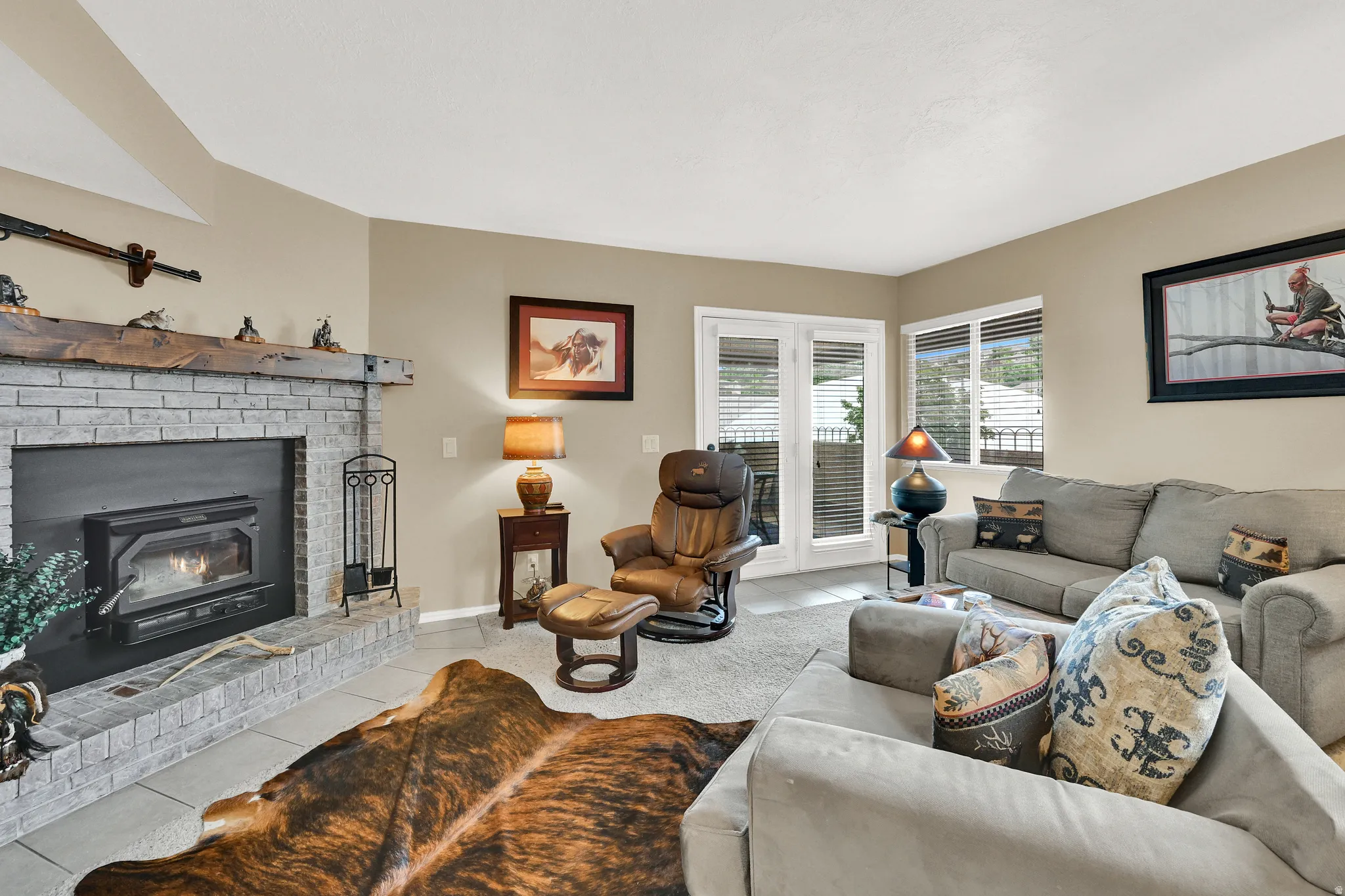 Spacious living area featuring a brick fireplace with a wood mantle, a wood-burning insert, and tile hearth