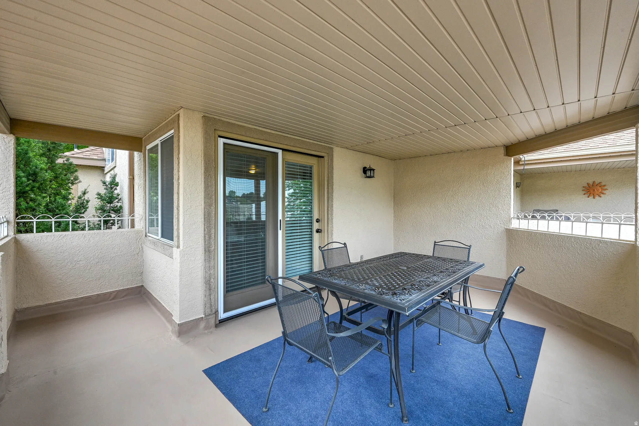 Covered outdoor patio area featuring a textured stucco finish and a sliding glass door entry