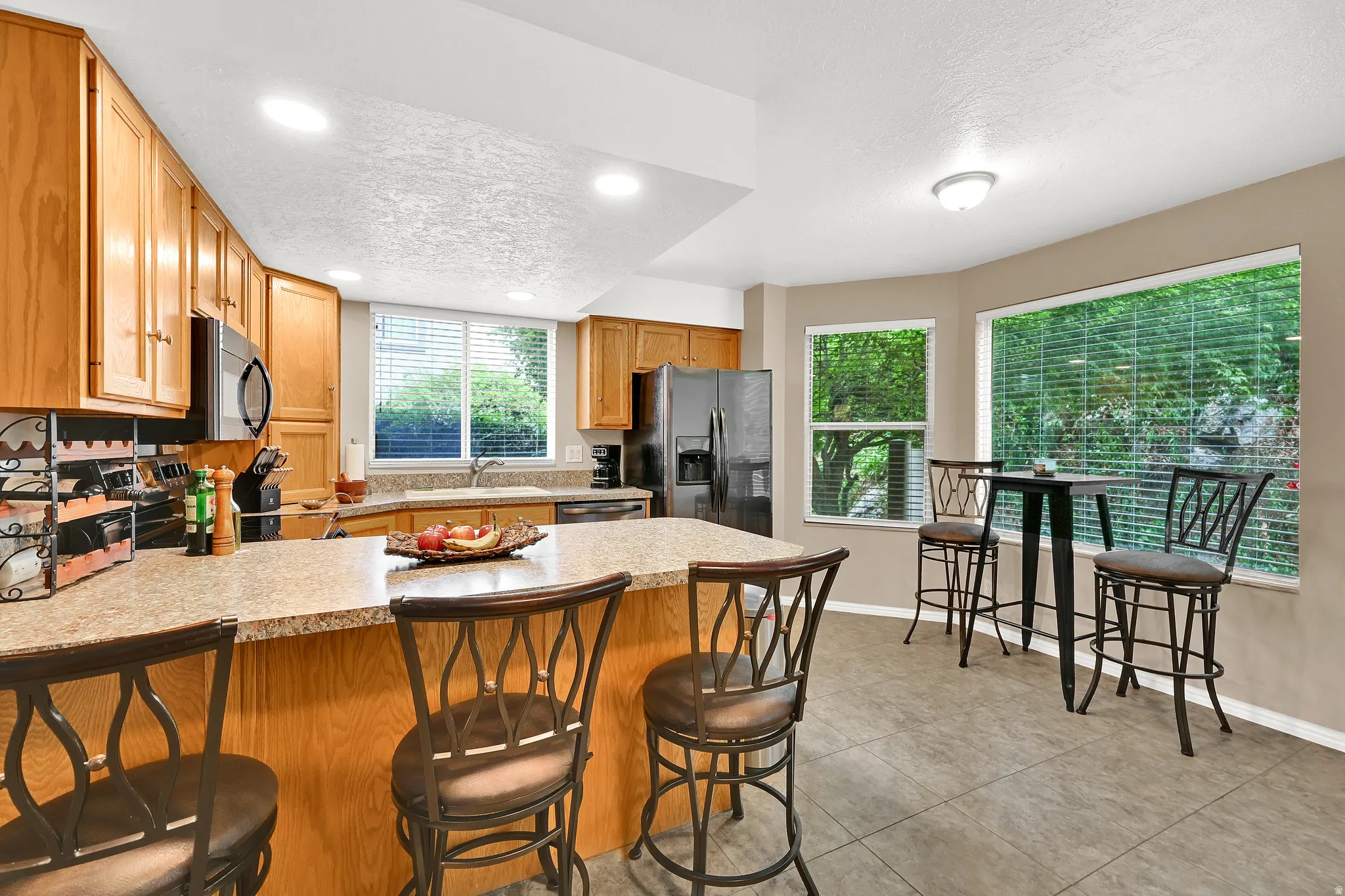 Kitchen featuring wood cabinetry, a built-in microwave, a black stainless steel refrigerator, and a double basin sink