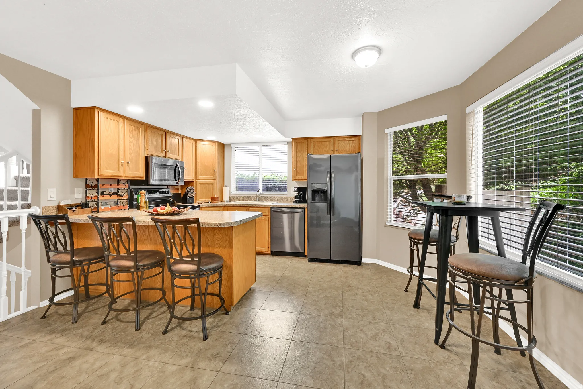 Kitchen featuring light wood cabinetry, stone countertops, stainless steel appliances, and tile flooring