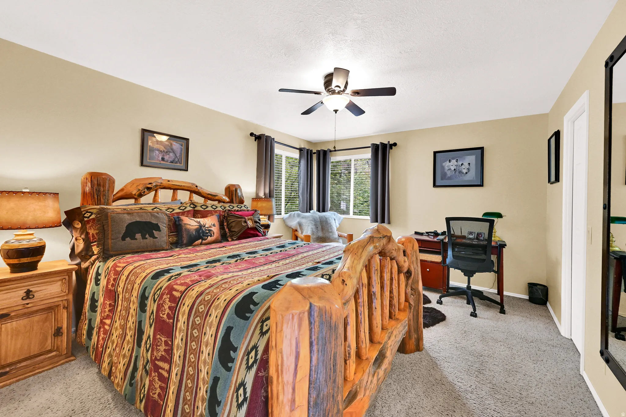 Spacious room featuring neutral-toned walls, plush carpet flooring, a ceiling fan, and window with dark curtains