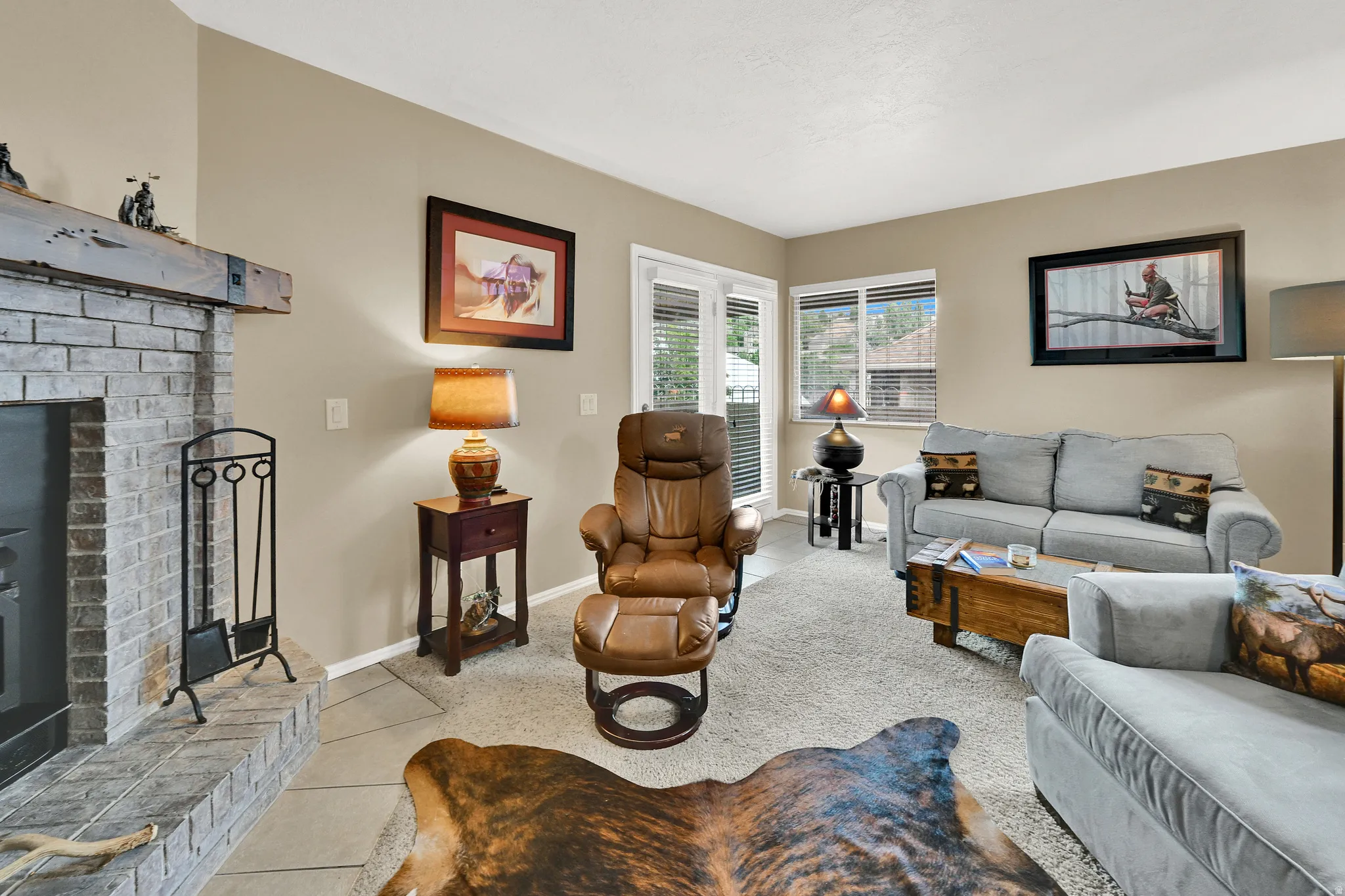 Living area featuring a floor-to-ceiling brick fireplace with a wood mantel, light tan wall color, and carpet flooring
