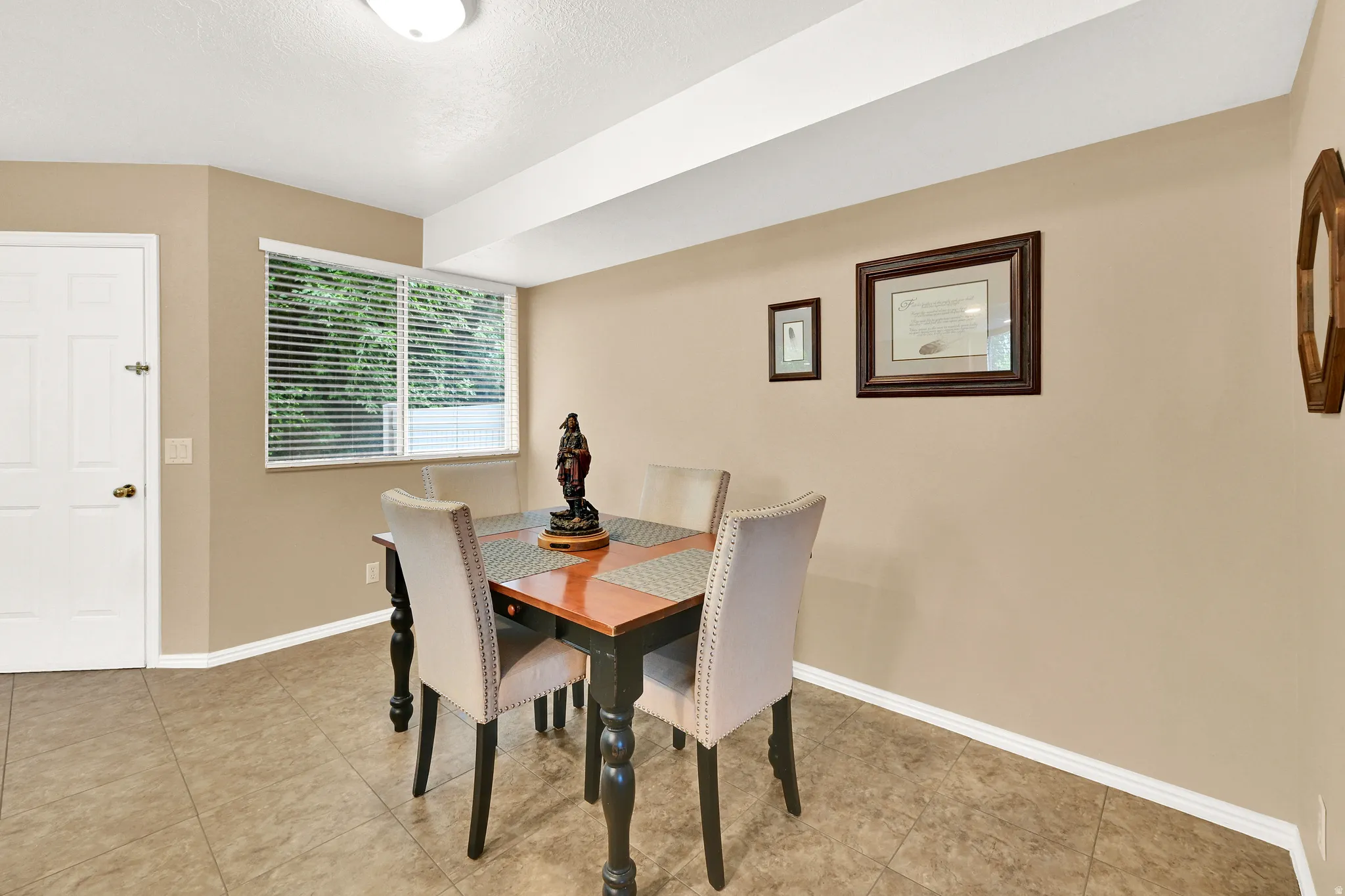 Dining area featuring neutral wall tones, tile flooring, a white window frame with blinds, and white baseboards
