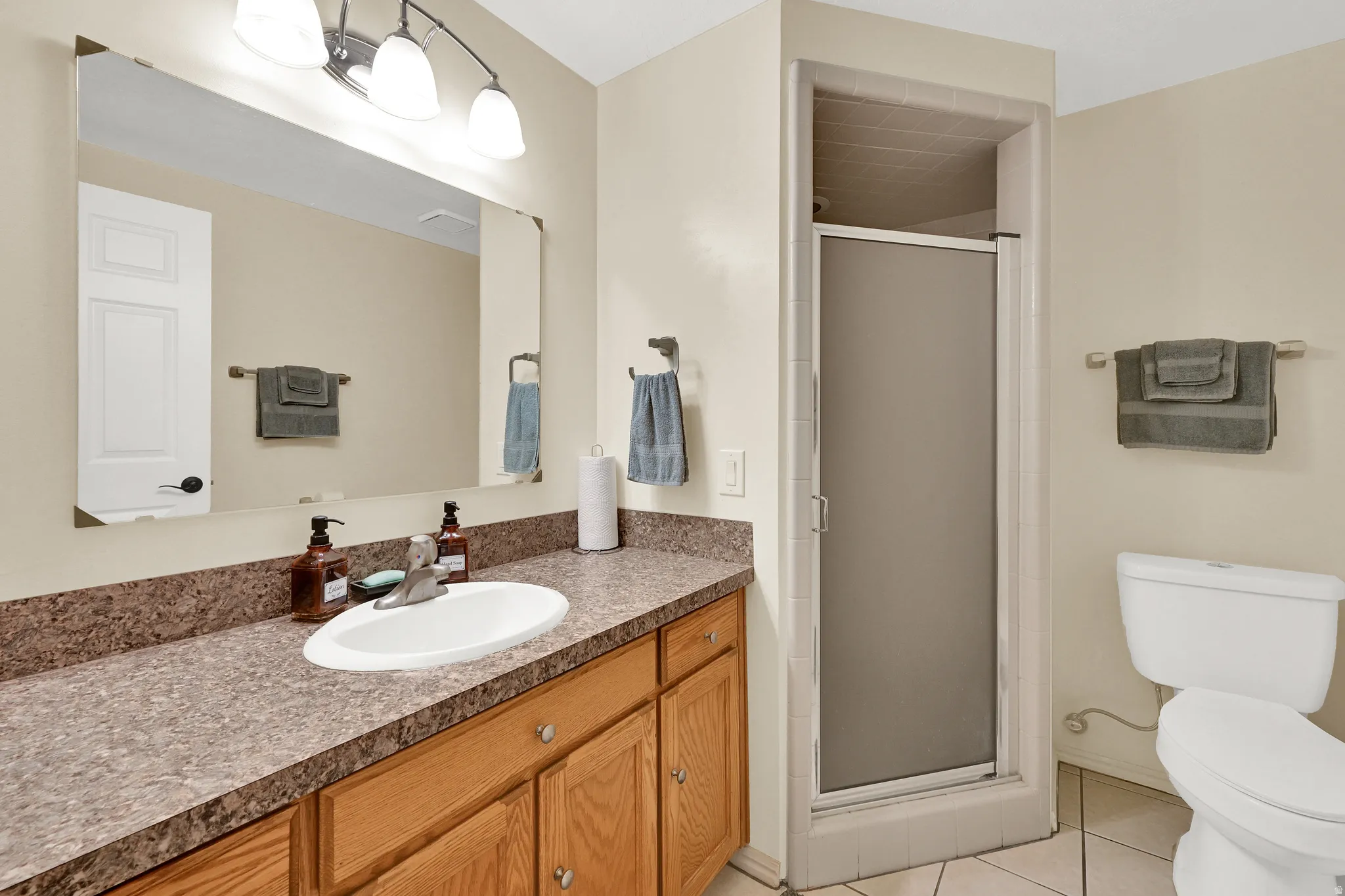 Bathroom featuring a wood-finish vanity with a built-in sink and a patterned countertop