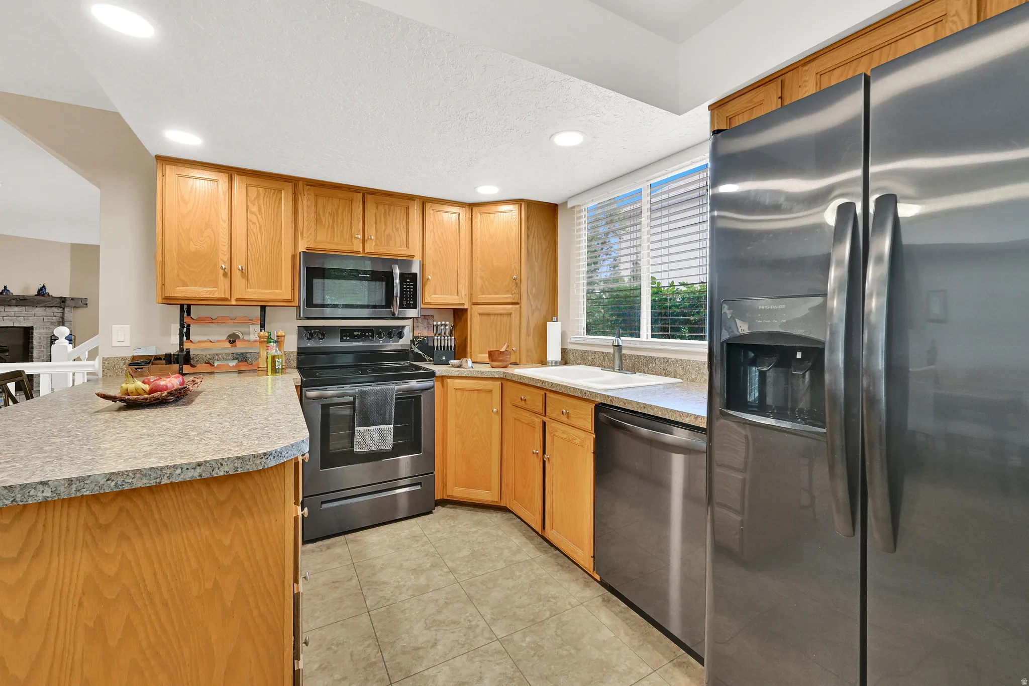 Kitchen featuring light wood cabinetry, stainless steel appliances, granite-look countertops, and recessed lighting