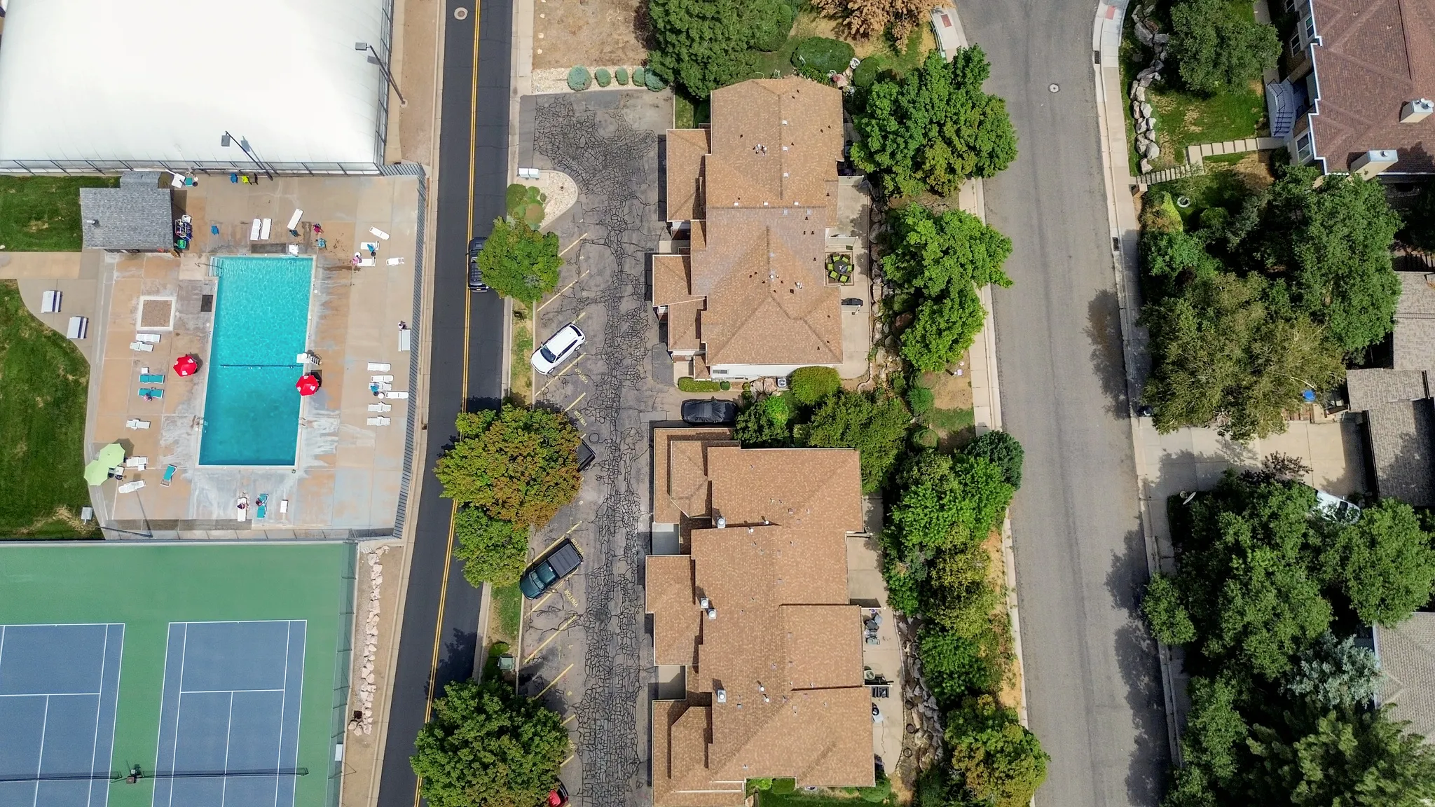 Community amenities including a swimming pool with surrounding deck, multiple tennis courts, and mature landscaping
