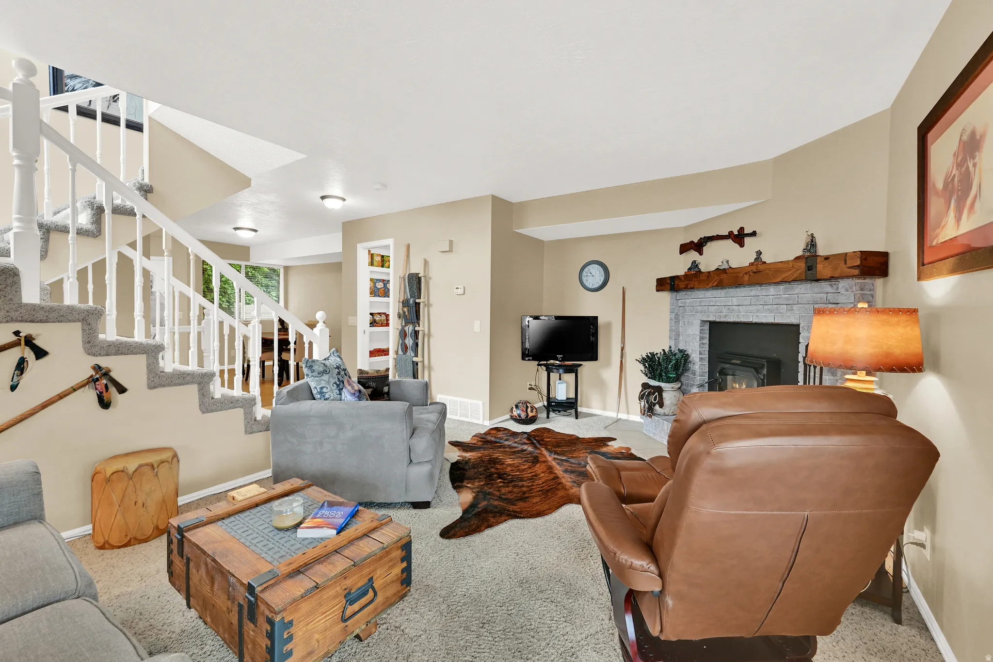 Living area featuring a textured fireplace with a wood mantle, an integrated built-in bookshelf, and a carpeted staircase with white balusters