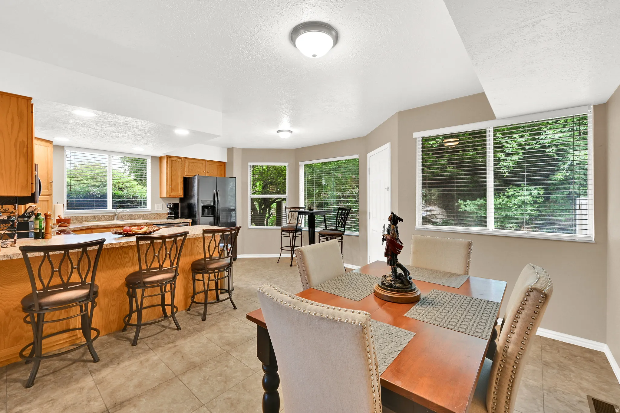 Open-concept kitchen and dining area featuring light wood cabinetry and a breakfast bar