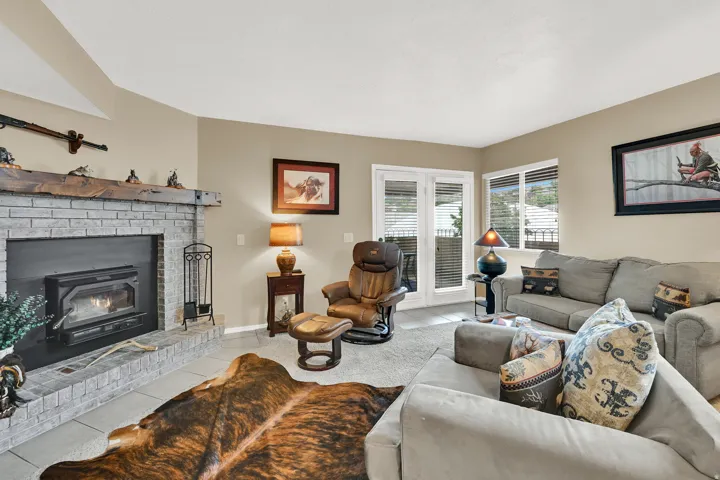 Spacious living area featuring a brick fireplace with a wood mantle, a wood-burning insert, and tile hearth