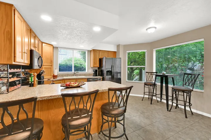 Kitchen featuring wood cabinetry, a built-in microwave, a black stainless steel refrigerator, and a double basin sink