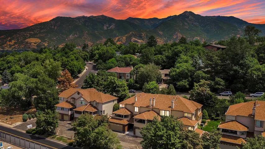 roofs complement the stucco exteriors of these multi-story residences, nestled among mature trees